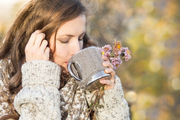Девушка пьет чай и трав осенью 