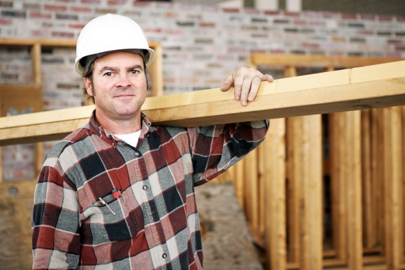 Мужчина-строитель с деревянной балкой